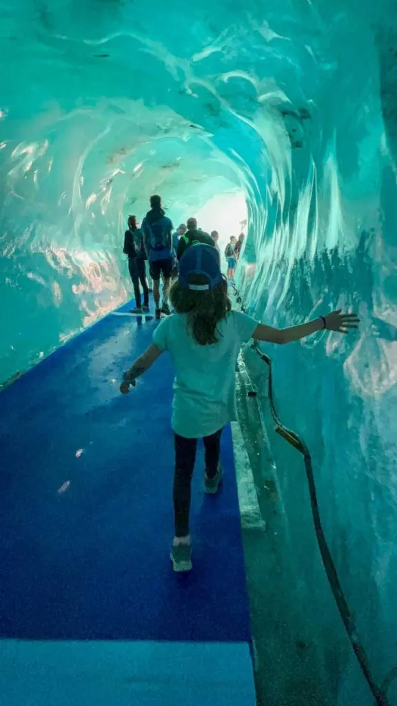 a girl feels the freezing ice walls of the Chamonix ice caves during a family summer trip to France