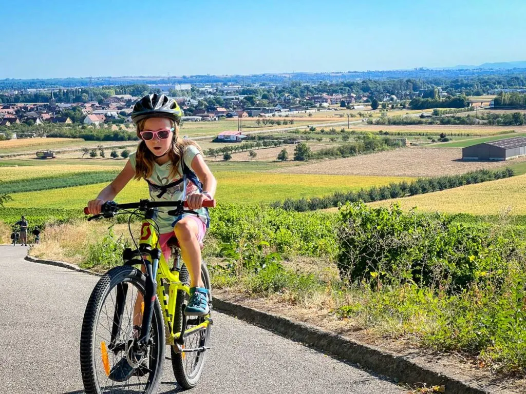 a 9 year old girl works hard to cycle up a hill on a family bike trip in Alsace, France