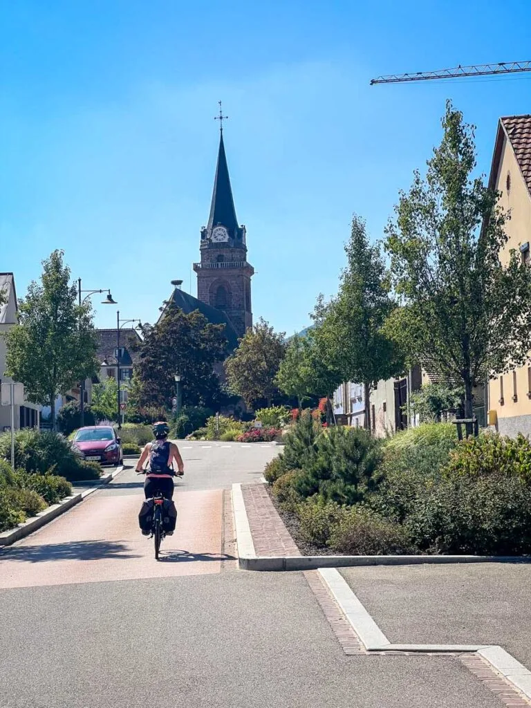 a female cyclist explores a French village in the Alsace wine region