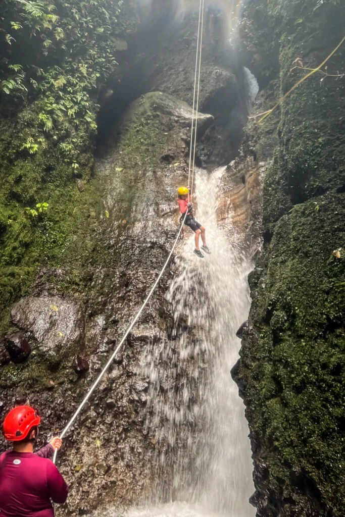 a young girl rappels through a waterfall in La Fortuna, Costa Rica