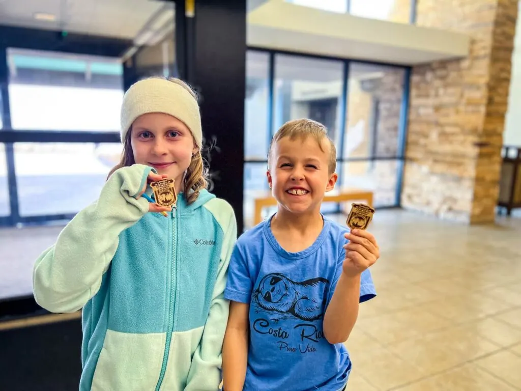 Two kids proudly show off their Carlsbad Caverns junior ranger badges.