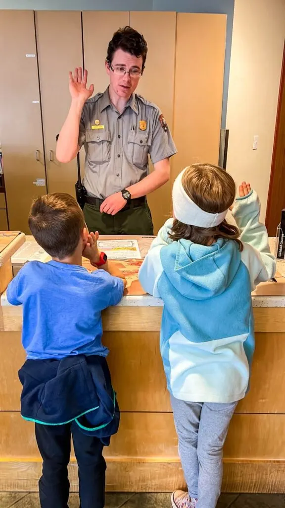 A park ranger at the Carlsbad Caverns National Park leads two children in the junior ranger oath.