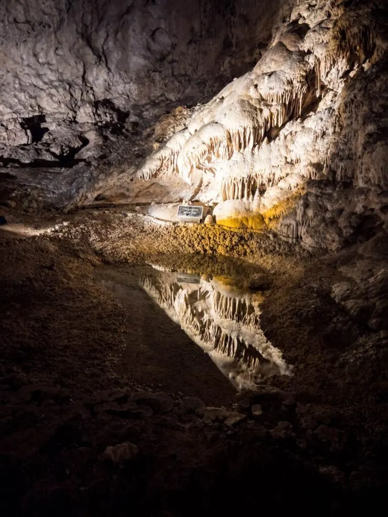 A beautiful formation at Carlsbad Caverns is reflected in the water of a still pool.