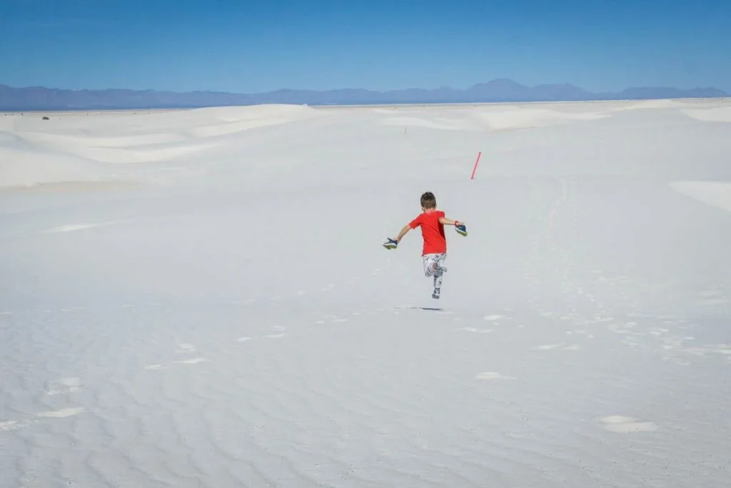 a young boy runs in the sand on the Alkali Trail at White Sands National Park.