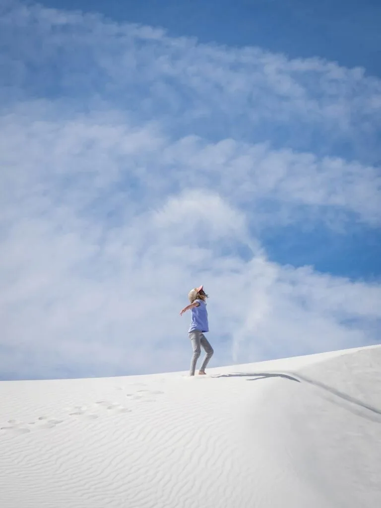 a girl throws sand for an interesting picture while on a family hike at White Sands National Park.