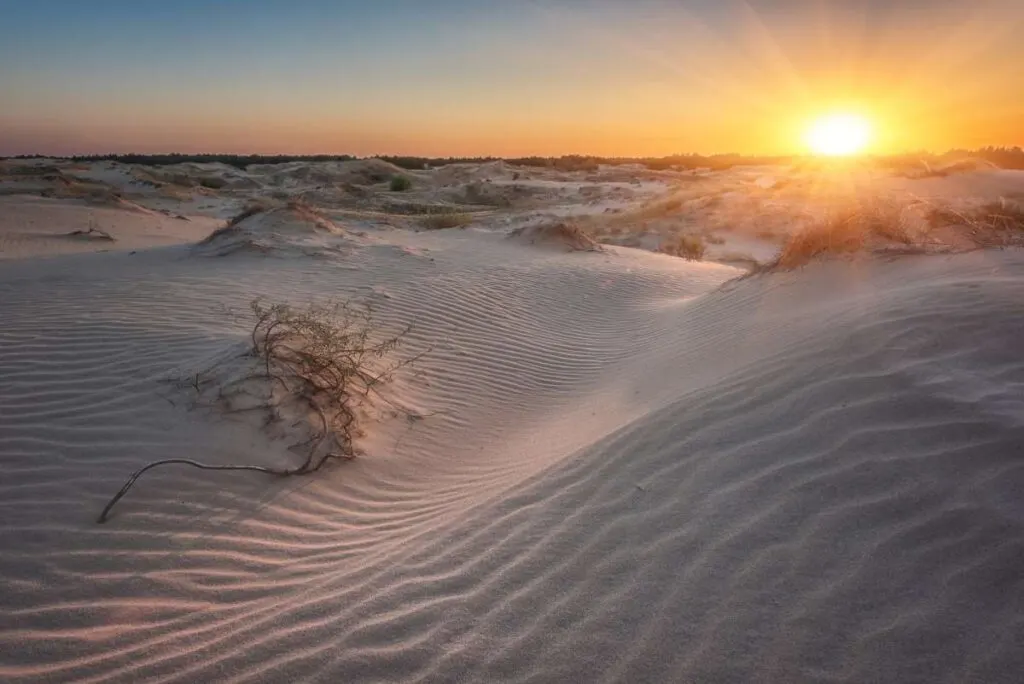 a colorful sunset creates shadows on the dunes at White Sands National Park.