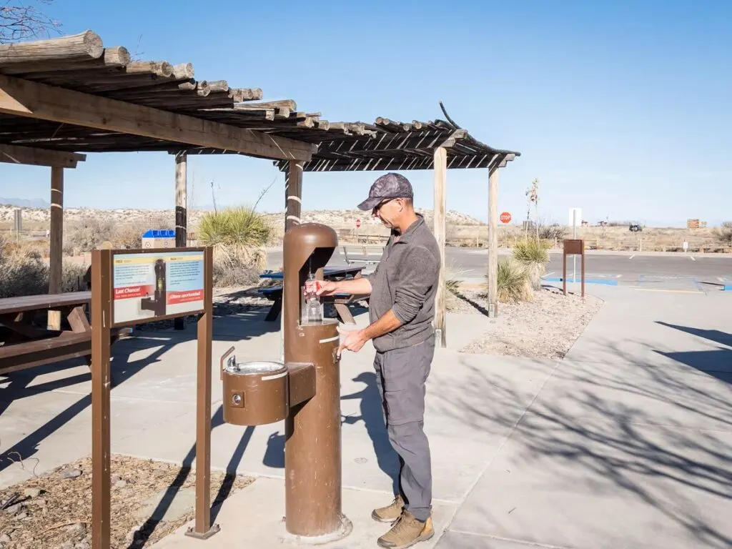 a man fills his water bottle at the White Sands visitor center.