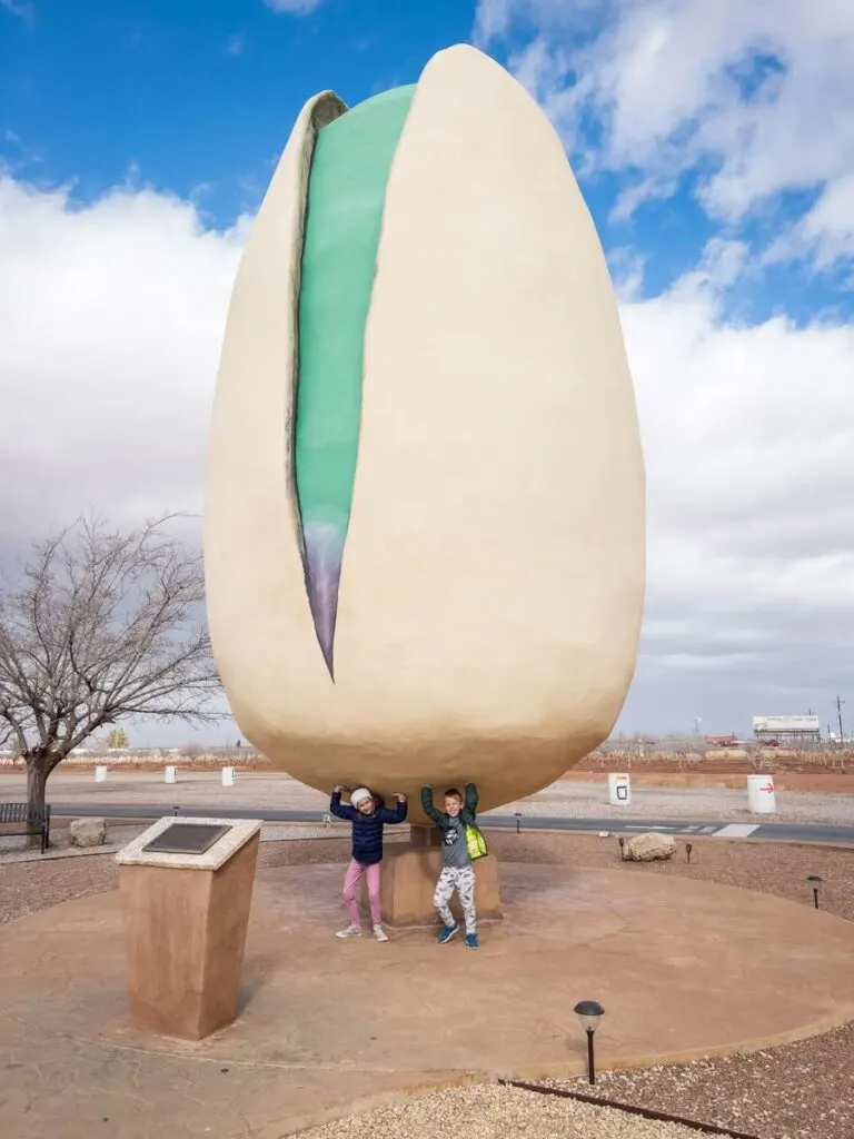 Two kids pretend to hold up the World's Largest Pistachio in Alamogordo, NM.