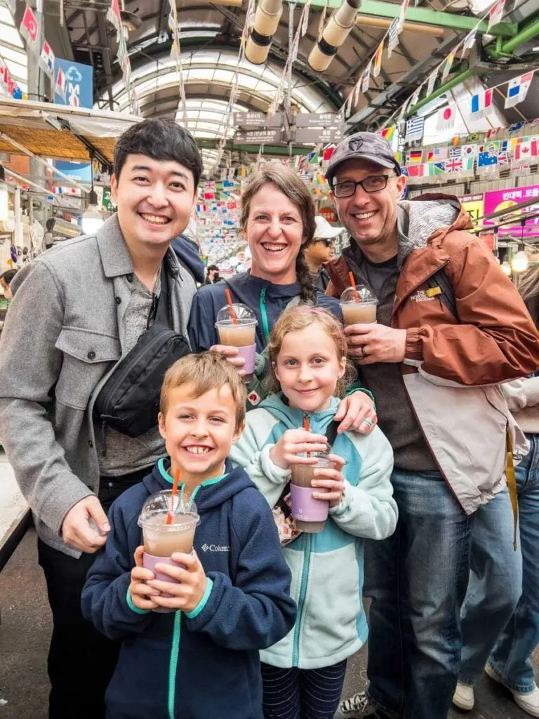 a happy family takes a picture with their guide on a family Seoul food tour to Gwangjang Market.