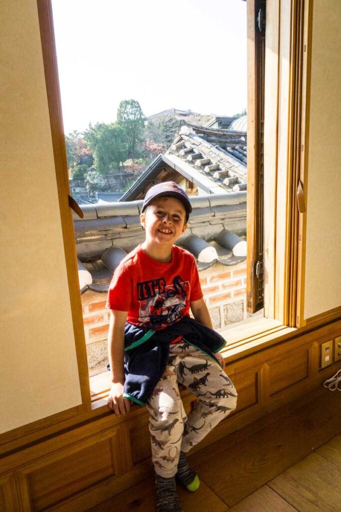 a young boy sits on a ledge in a traditional house in the Bukchon Hanok Village.