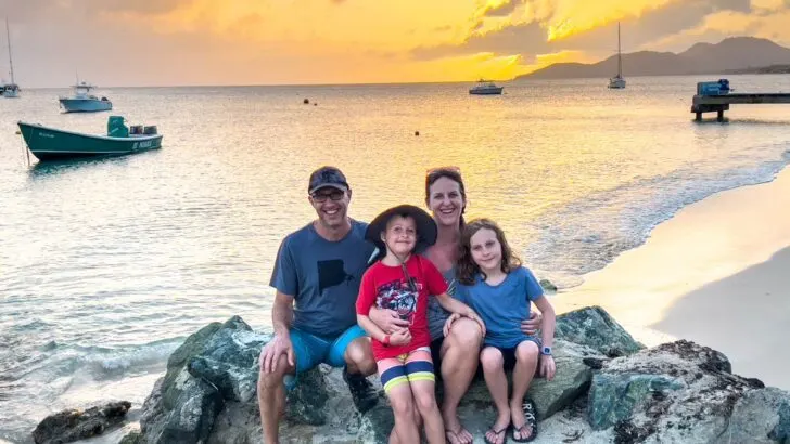 A family sits on a rocks at sunset on a beach while spending a week with kids in Vieques, Puerto Rico.