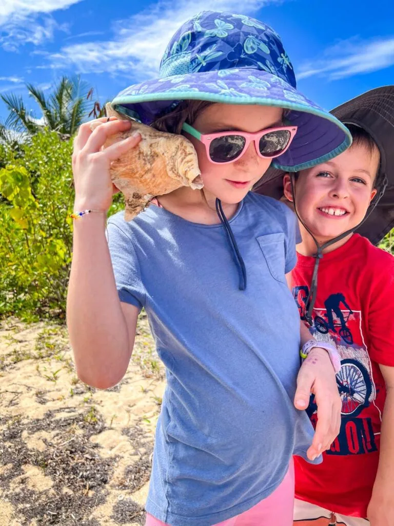 a young girl listens to the ocean with a conch shell she found on a family hike in Vieques.