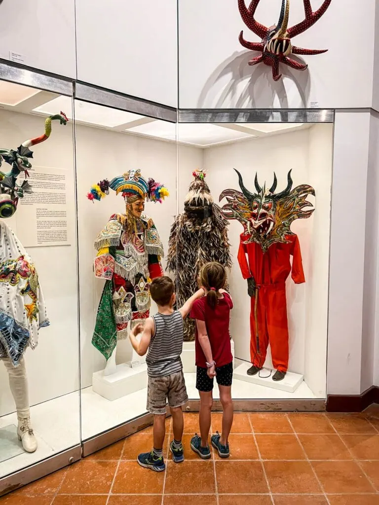two children enjoy colorful costumes on display at the Museo de las Américas while on a family vacation to Puerto Rico.