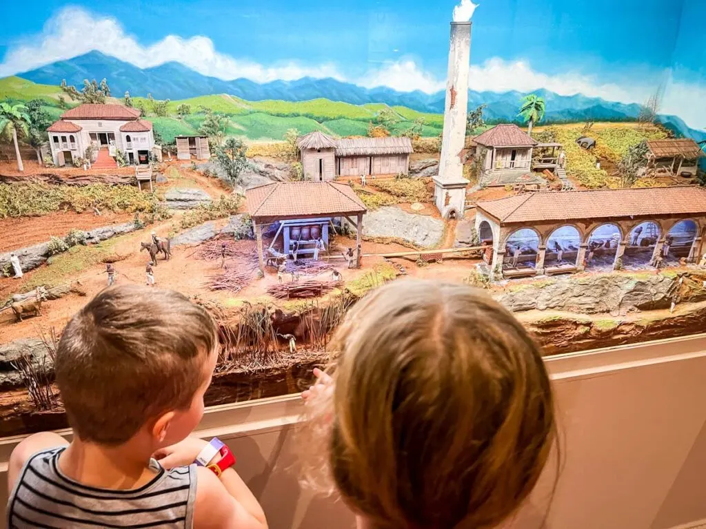 two kids look at a diorama of a traditional Puerto Rican village at a kid-friendly museum in San Juan.