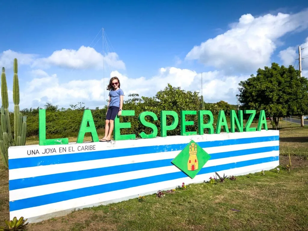 a girl stands on the La Esperanza welcome sign in southern Vieques, Puerto Rico.