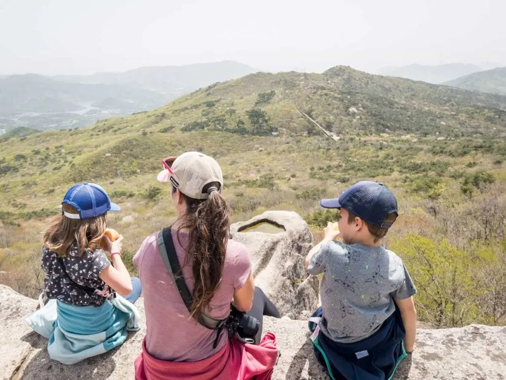 a family enjoys a scenic picnic lunch on a kid-friendly hike near Busan, Korea.
