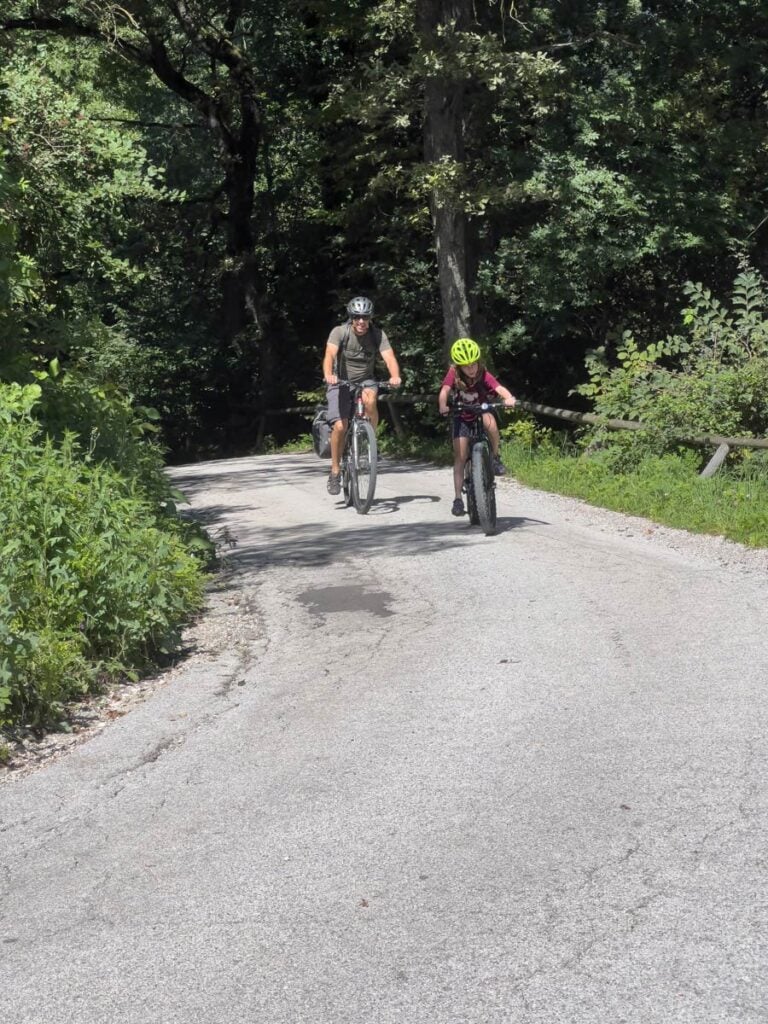 a family works hard cycling up a long hill during a self-guided bike tour around Bled, Slovenia.