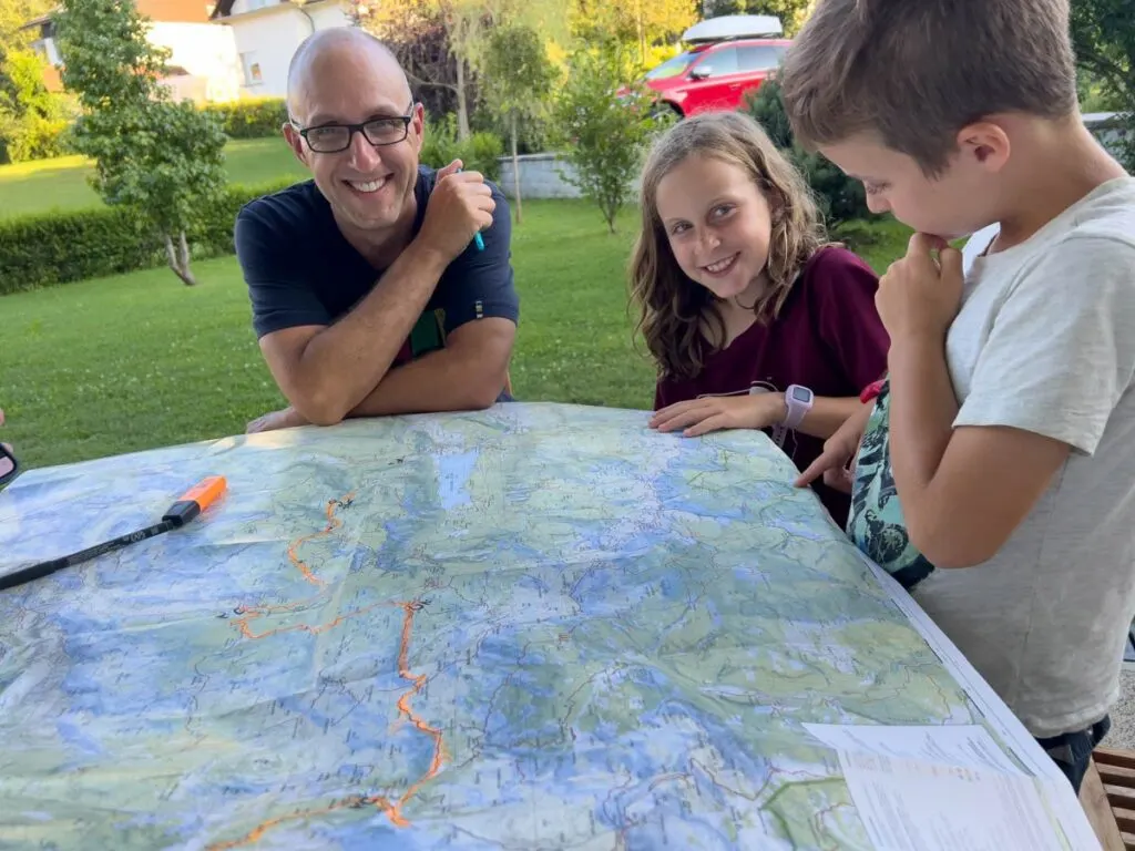 a family looks at their hiking plans for their upcoming hut to hut hiking tour in Slovenia with kids.