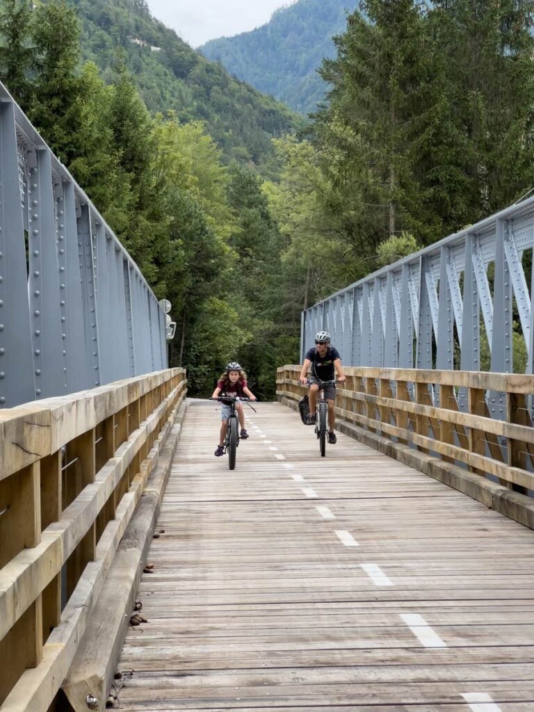 a family cycles across a bridge on their way to Kranjska Gora, Slovenia.