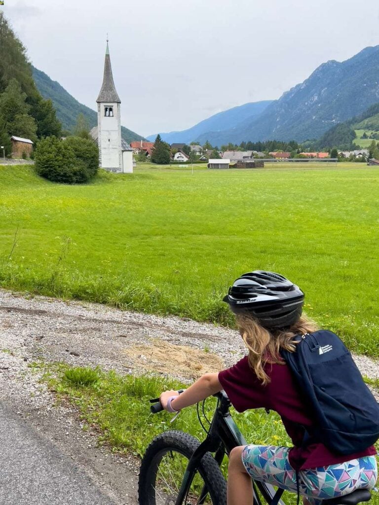 a girl cycles past a church on a self-guided bike tour in Slovenia.