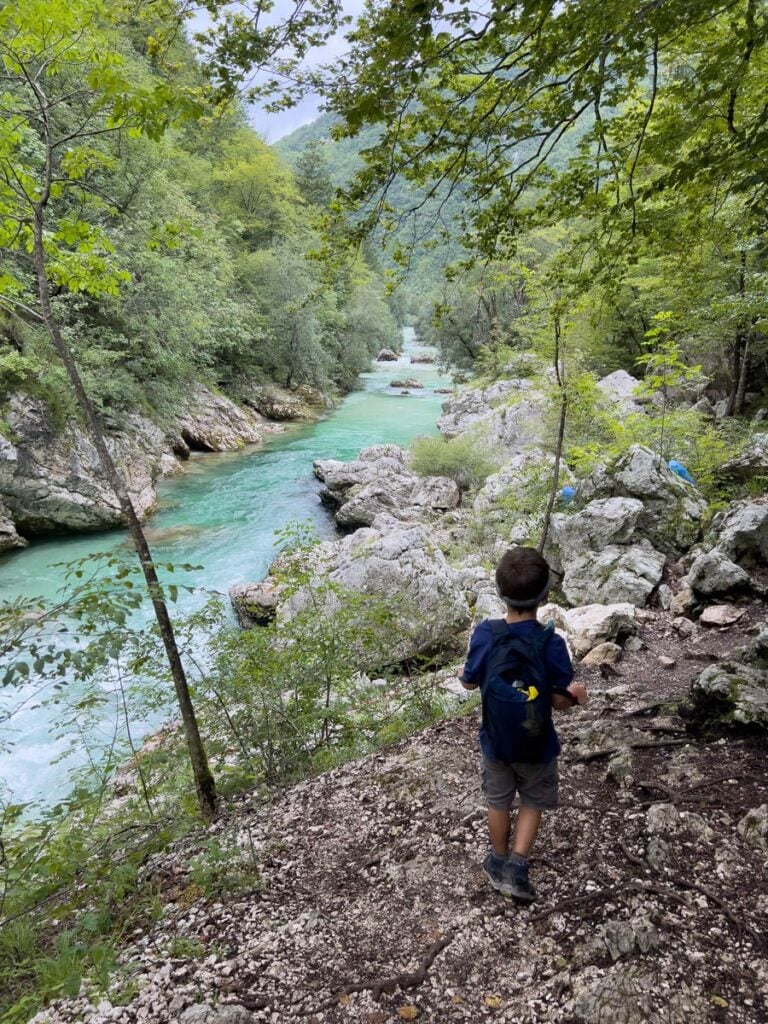 a young hiker walks along the Soca River on a family hike to Bovec, Slovenia.