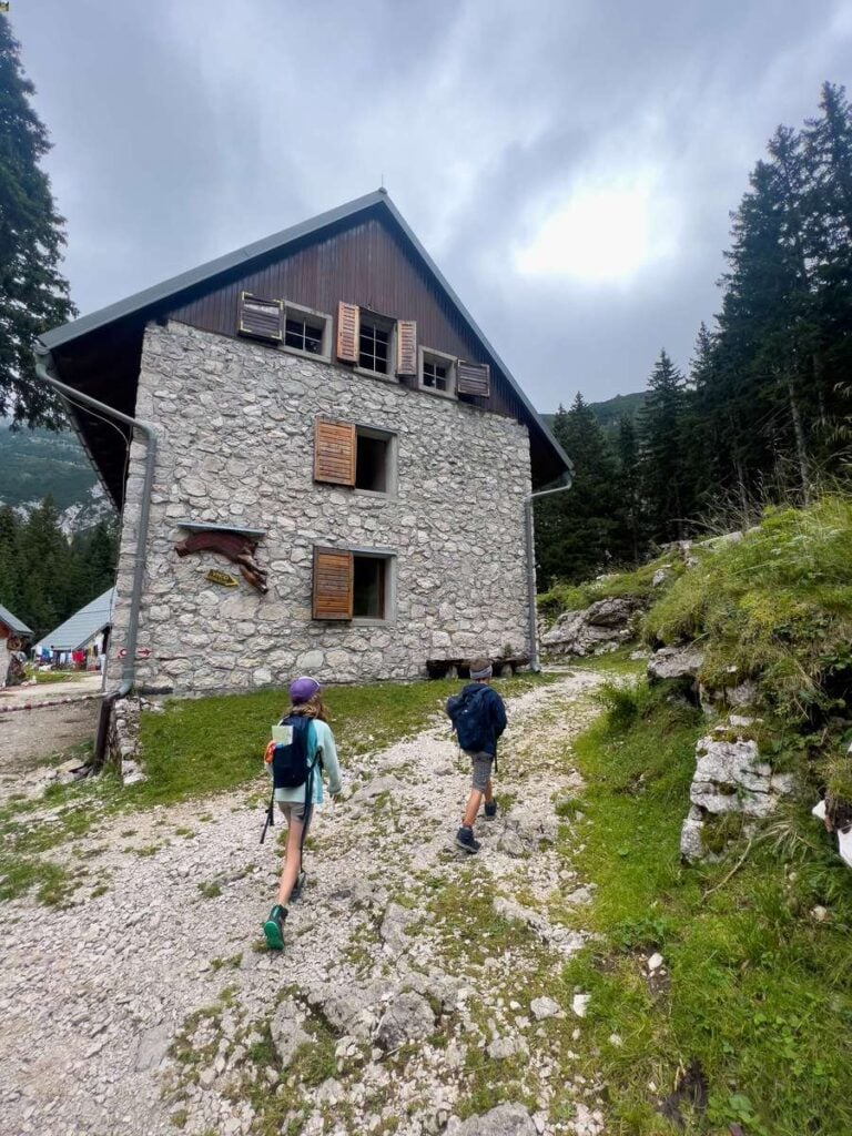 a family of hikers arrives at the Krn Lake hut in the Julian Alps.