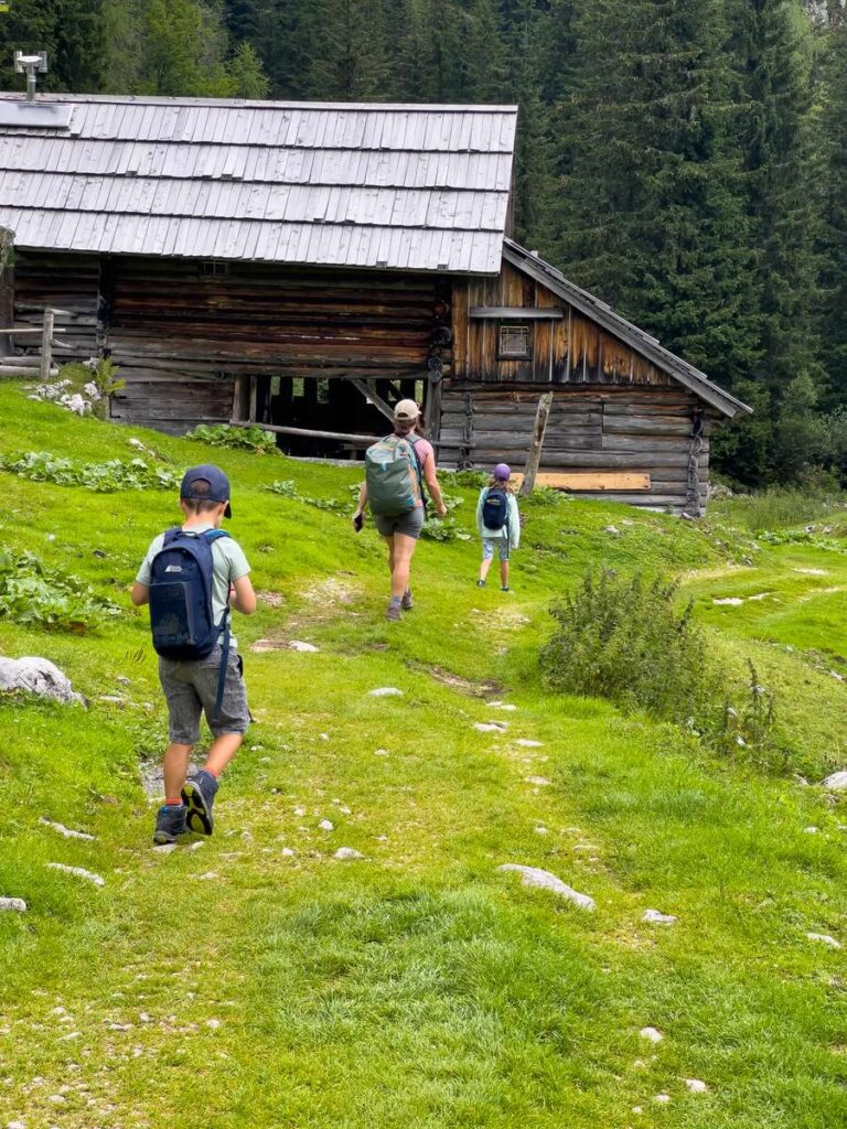 a family hikes past an abandoned building on a hut to hut hiking tour in the julian alps.