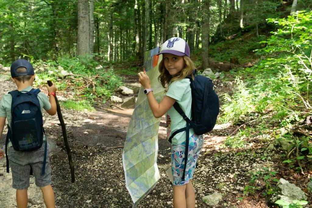 a young hiker consults her trail map while hiking at Blato Pasture, Slovenia.