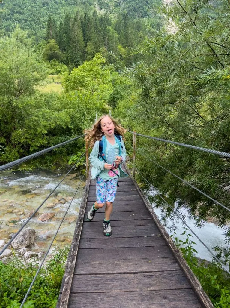a girl plays around while running across a suspension bridge in the julian alps in Slovenia.