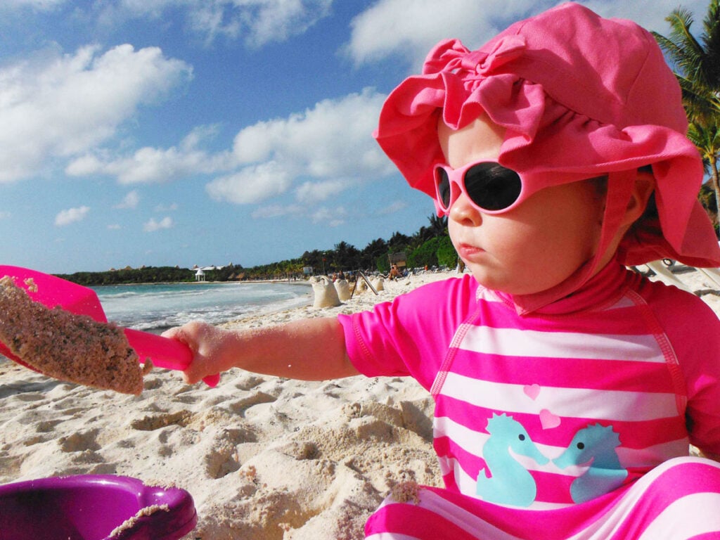 The daughter from Family Can Travel enjoys playing in the sand on her first family trip to Mexico.