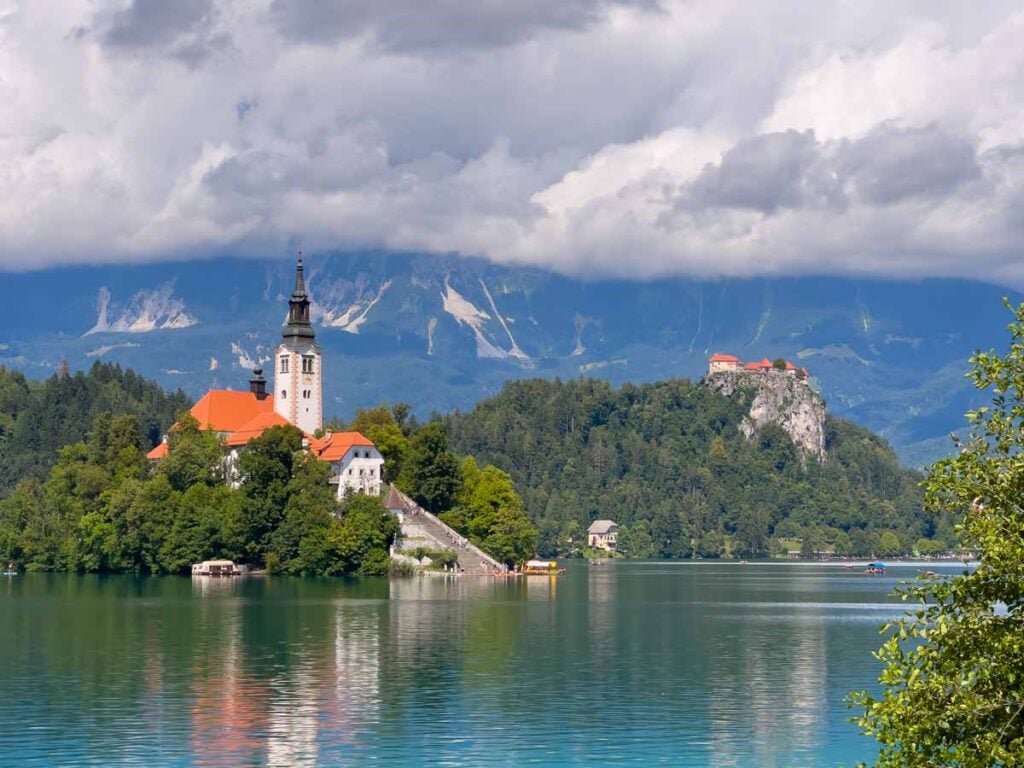 the Assumption of Maria Church on an island on Lake Bled, with the Bled Castle in the background.