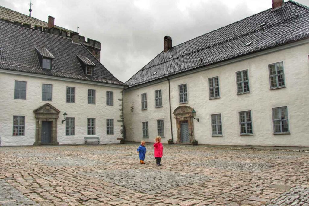 Two small kids explore the Bergenhus Fortress while on a family vacation to Bergen, Norway.