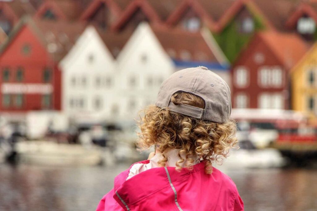 a 4-year old girl on a family trip to Bergen looks at Bryggen across the water.