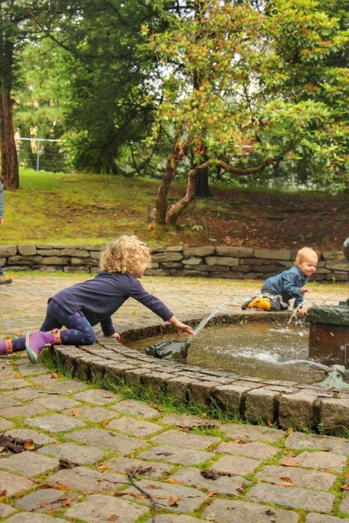 Two kids in a water fountain in Nygardsparken in Bergen Norway.