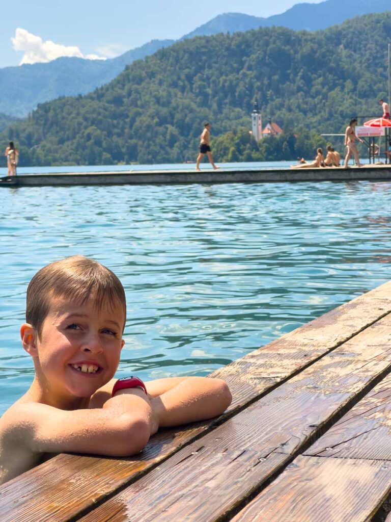 an 8-year old boy enjoys swimming in the Castle Bathing Area during a family vacation to Lake Bled, Slovenia.