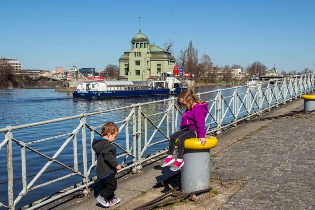 The Brewer kids, from the FamilyCanTravel.com blog, play on the Vltava River Promenade while enjoying an easy family walk in Prague.