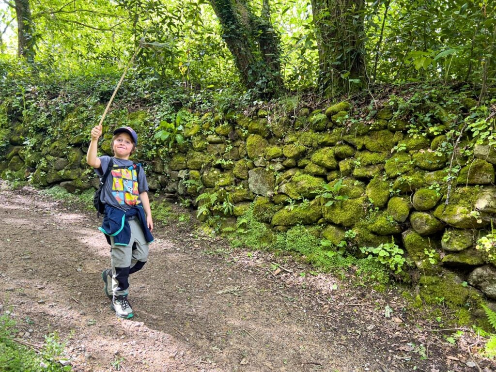 A happy 8-year old boy plays with a stick while on a self-guided Camino tour with his family.