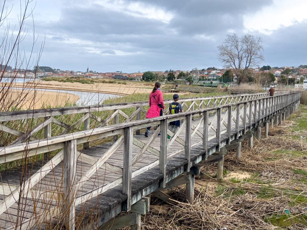 Celine Brewer, owner of FamilyCanTravel.com, walks along a boardwalk with her child while hiking the Portuguese Coastal Camino together.