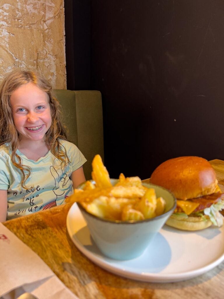 A 10-year old girl smiles before eating her hamburger in Spain.