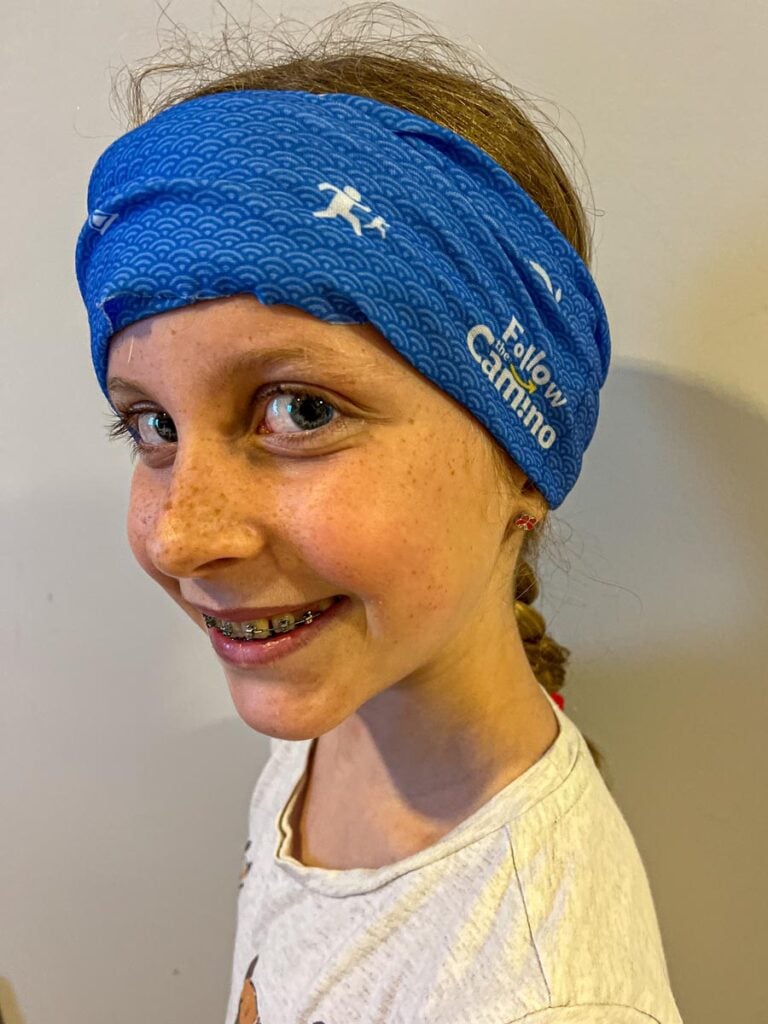 A 10-year old girl models her Follow the Camino buff before beginning a 6-day family-friendly Camino pilgrimage with her family.