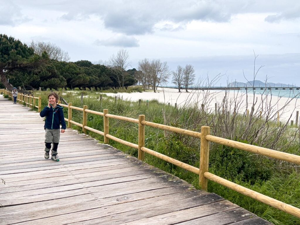 An 8-year old boy walks along a beach boardwalk nearing the end of the second leg of the camino portuguese coastal route.