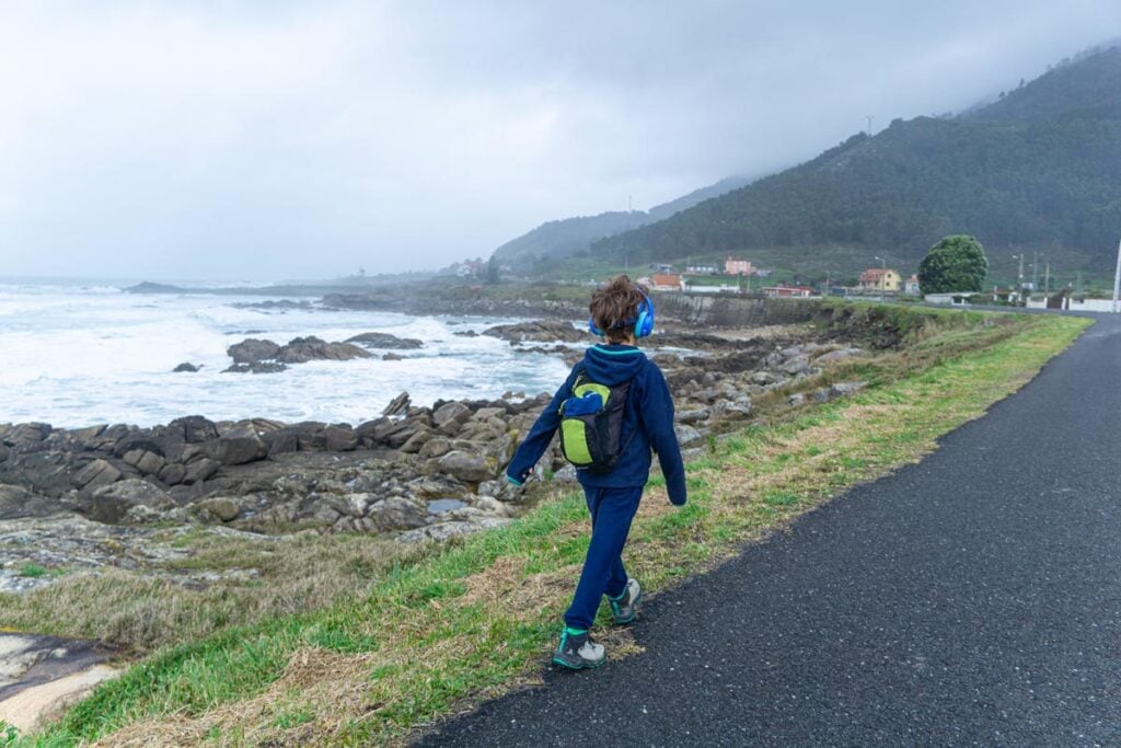 an 8-year old boy wears his own small day bag while hiking the Portuguese Coastal Camino Trail with his family.