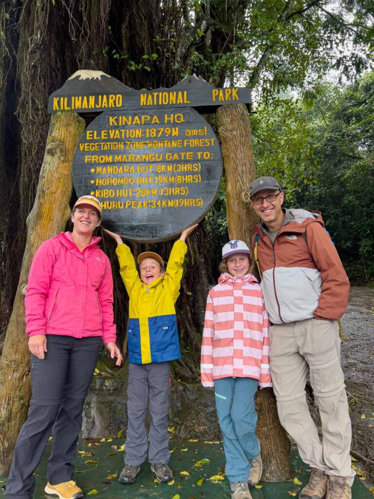 The Brewer family, from the Family Can Travel blog, poses for a photo at the Marangu Gate in Mount Kilimanjaro National Park, Tanzania.