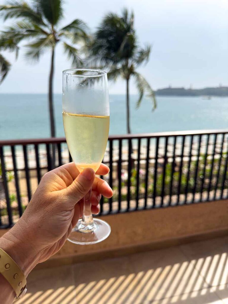 a glass of champagne with palm trees with Tangolunda Bay, Mexico.