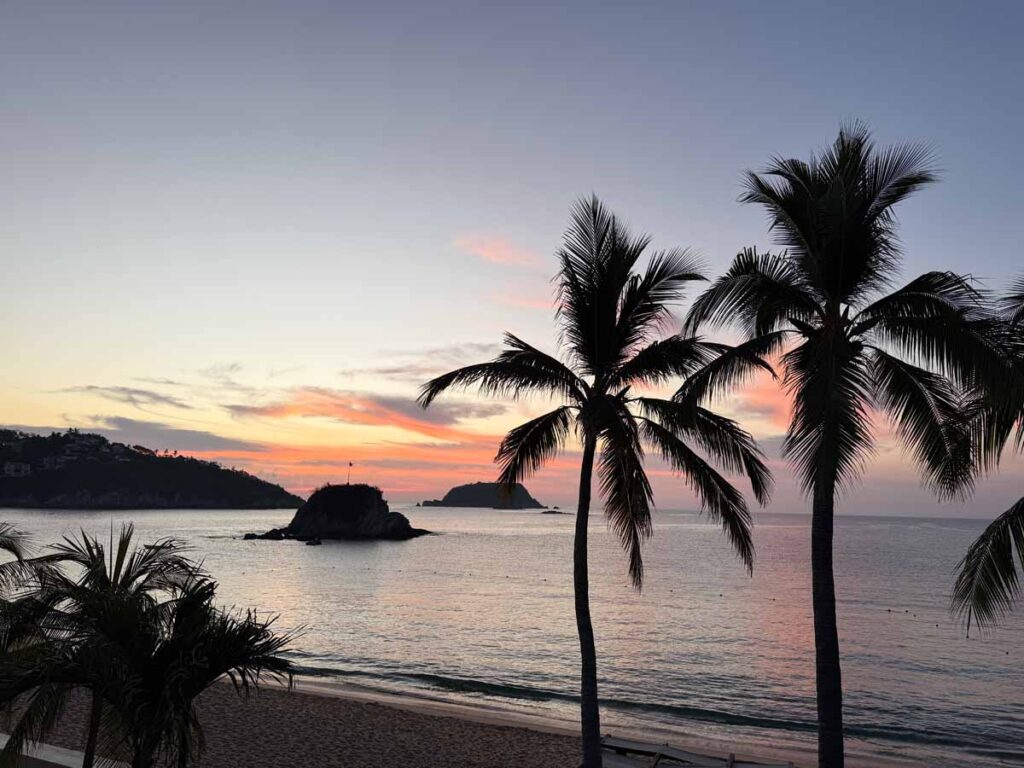 palm trees sway in the breeze at sunrise over Tangolunda Bay at the Barcelo Huatulco all-inclusive resort.
