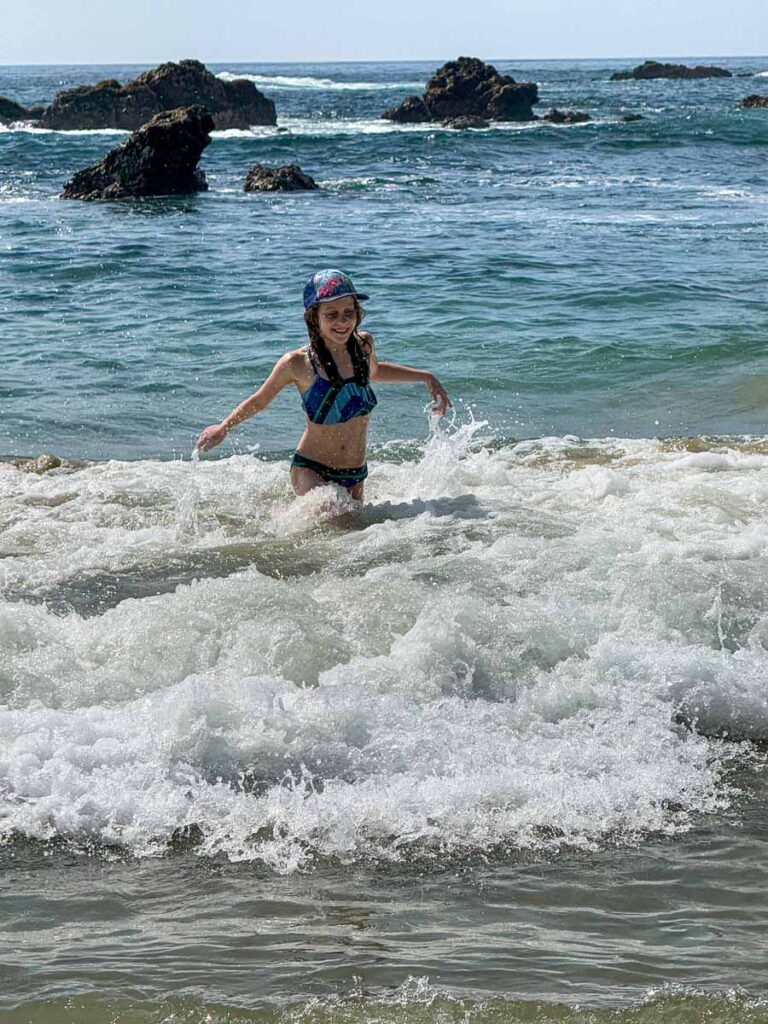 a 10-year old girl plays in the small waves at Playa San Agustinillo, Oaxaca, Mexico.