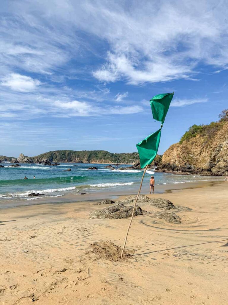 Green flags fly at Playa San Agustinillo, indicating the water is safe to swim in.