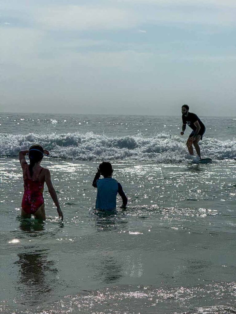 The Brewer kids from the FamilyCanTravel.om blog, watch a surfer from the safe water at Playa San Agustinillo.