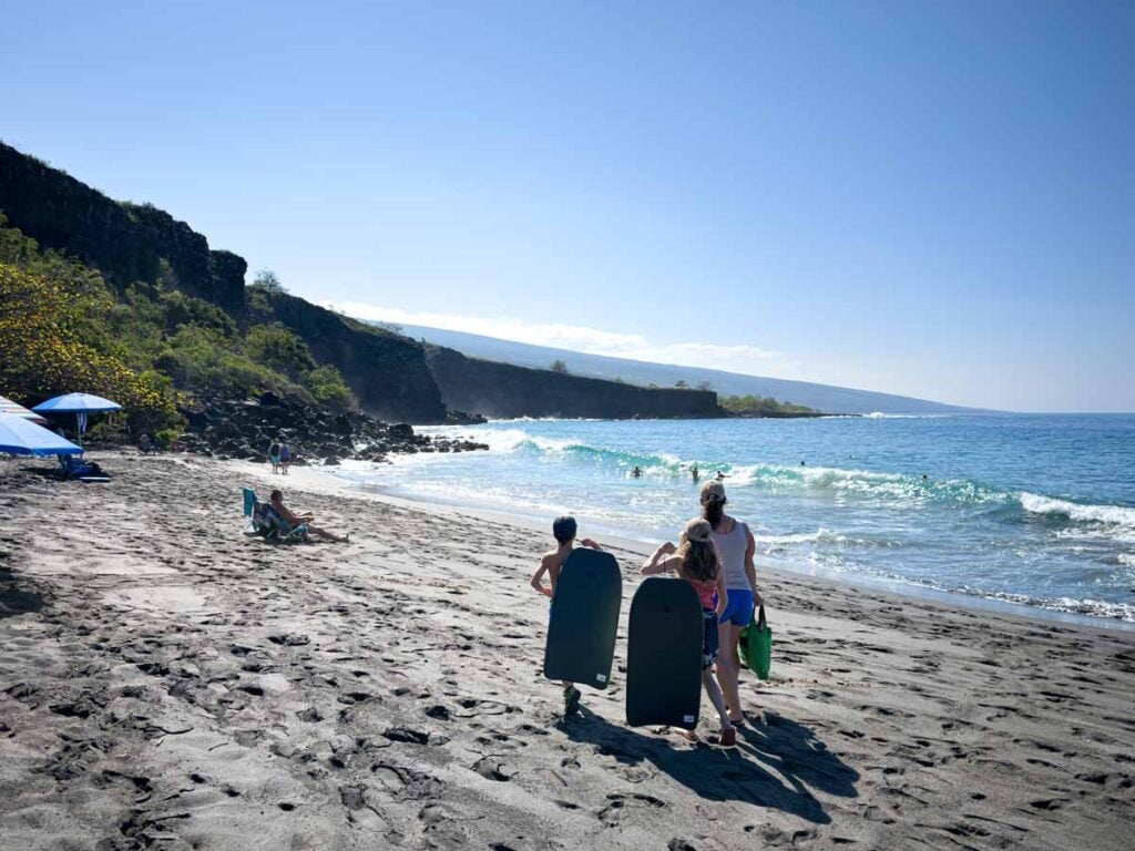 Celine Brewer walks with her kids to Ho’okena Beach Park on the Big Island of Hawaii for some boogie boarding in the surf.