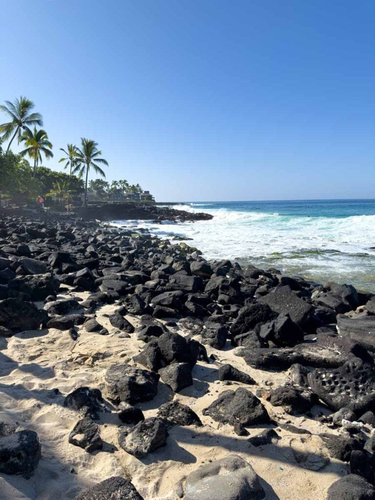 Black rocks line the beach at La‘aloa Beach Park (“Magic Sands Beach” or “White Sands Beach”) on the Big Island of Hawaii.